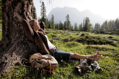 a woman sitting next to a tree with a backpack at Chalet Rotenstein in Berwang