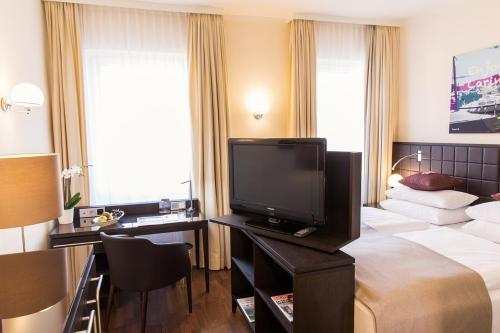 a hotel room with a bed and a flat screen tv at Hotel Sandwirth in Klagenfurt