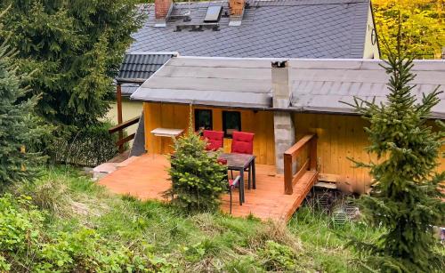 a house with a deck with a table and red chairs at Ferienhaus-Elisabeth Bungalow-Tom Bungalow-Peter in Reinhardtsdorf