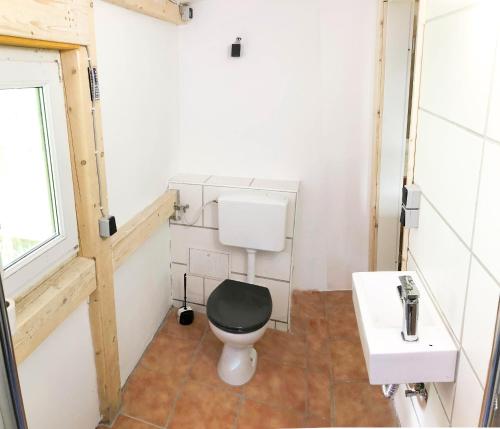 a bathroom with a black toilet and a sink at Ferienhaus-Elisabeth Bungalow-Tom Bungalow-Peter in Reinhardtsdorf