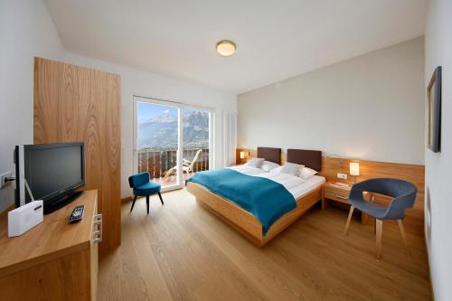 Habitación de hotel con cama y TV en Landhaus Weger, en Merano