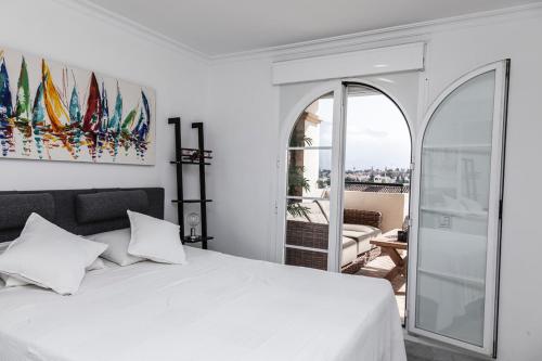 1 dormitorio con cama blanca y balcón en Señorío de Aloha Apartahotel, en Marbella