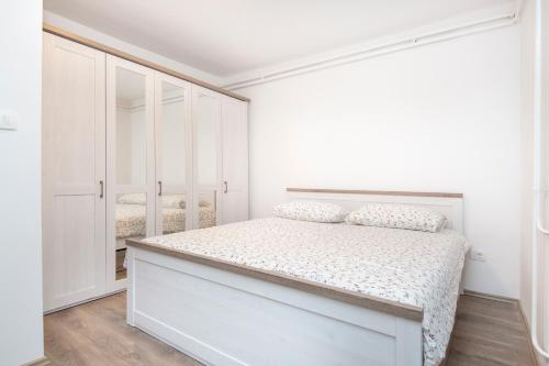 a white bedroom with a bed and white cabinets at Apartman Alberti in Labin