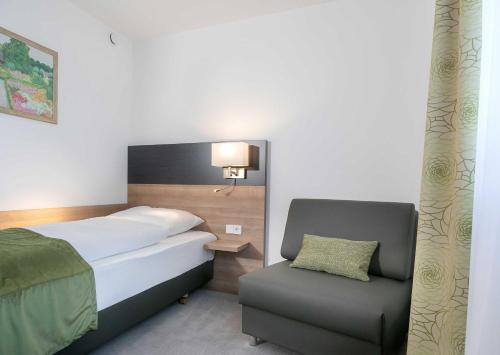 a bedroom with a bed and a chair at Hotel Kern garni in Walddorf
