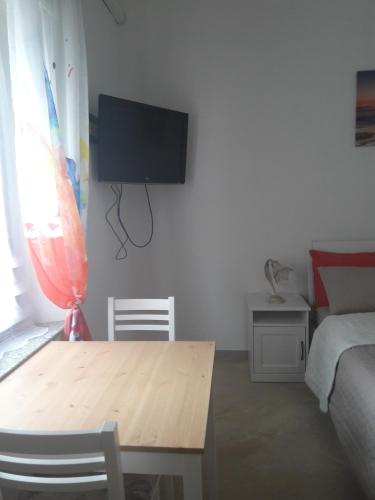 a living room with a table and a tv on a wall at Casa Corona in Capoterra