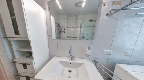 a white bathroom with a sink and a mirror at Schloonseevilla mit Tiefgarage - 200 m zum Strand in Heringsdorf
