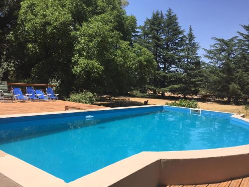 una gran piscina con sillas azules y árboles en Hostería La Península en Villa Ventana