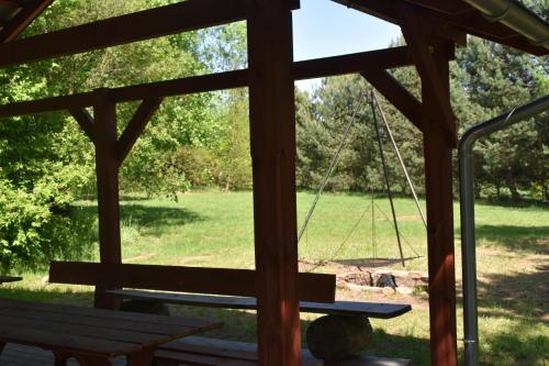 a swing in a gazebo with a view of a park at Newland Wójtowicz in Debrznica