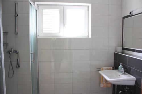 ein Badezimmer mit Dusche und Waschbecken und einem Fenster in der Unterkunft Apartment Pinta in Pag