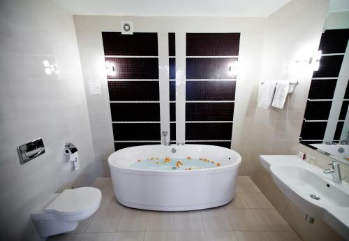 a white bathroom with a tub and a toilet and a sink at Hotel Tarnovia in Tarnów