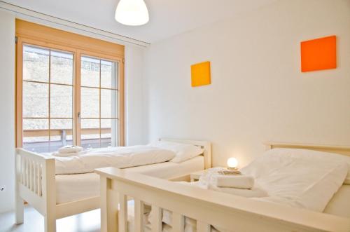 1 Schlafzimmer mit 2 Betten und einem Fenster in der Unterkunft Apartment Alpha - GRIWA RENT AG in Grindelwald
