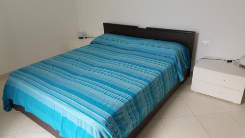 a bed in a room with a blue blanket on it at Le Case di Giorgia in San Vito lo Capo