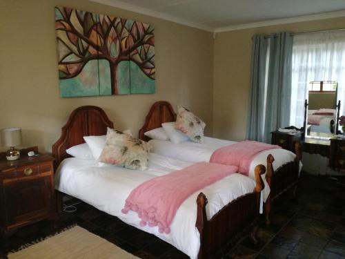 1 dormitorio con 2 camas y una pintura de árbol en la pared en Cadle House en Vryheid
