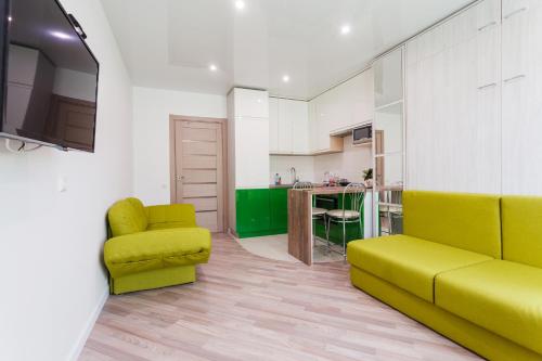 a living room with a green couch and a kitchen at Modern Studio Apartments in Kyiv