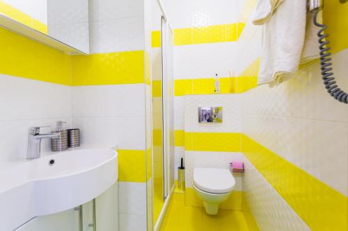 キーウにあるModern Studio Apartmentsの黄色と白のバスルーム(洗面台、トイレ付)