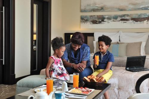 a woman and two children sitting on a couch at Pullman Lubumbashi Grand Karavia. in Lubumbashi
