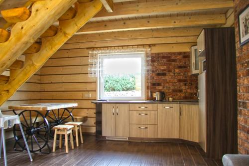 a kitchen in a log cabin with a table and a window at Bacówki nad jeziorem Goszcza in Lubrza