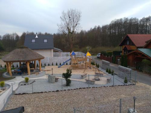 a small playground with a play area and a building at Bacówki nad jeziorem Goszcza in Lubrza