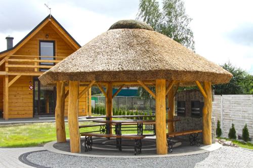 a wooden gazebo with a table and benches at Bacówki nad jeziorem Goszcza in Lubrza