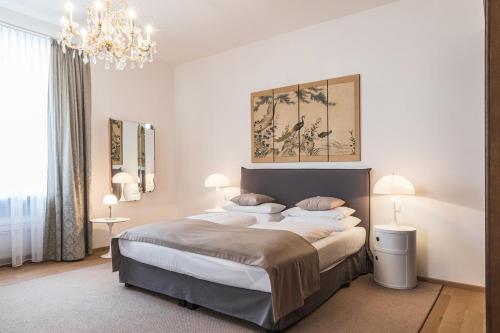 a bedroom with a large bed and a chandelier at Sandwirth Suites Palais Musil in Klagenfurt