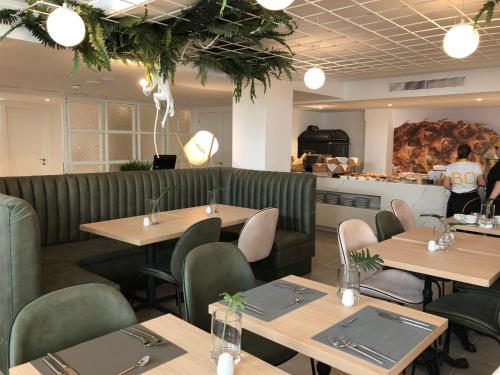 a restaurant with wooden tables and green chairs at BQ Paguera Boutique Hotel - Adults Only in Paguera