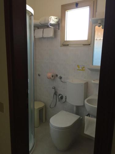 a bathroom with a toilet and a sink and a window at Hotel Erika in Caorle