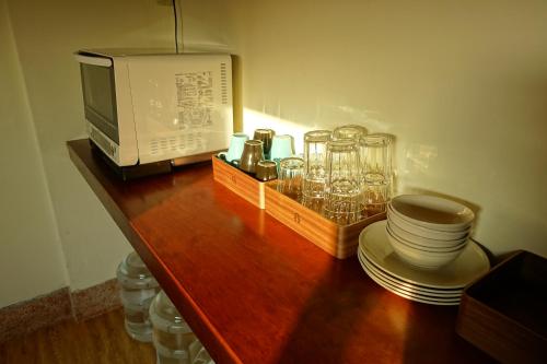 a wooden counter with a microwave and glasses on it at Chiayi Petite Hostel in Chiayi City