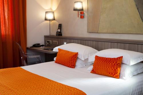 a hotel room with a bed with orange and white pillows at Best Western Plus Monopole Métropole in Strasbourg