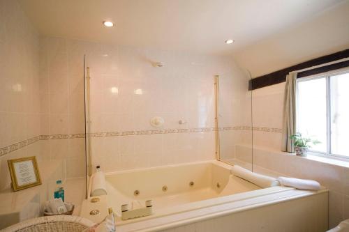 a bathroom with a bath tub and a window at Park Cottage in Warwick
