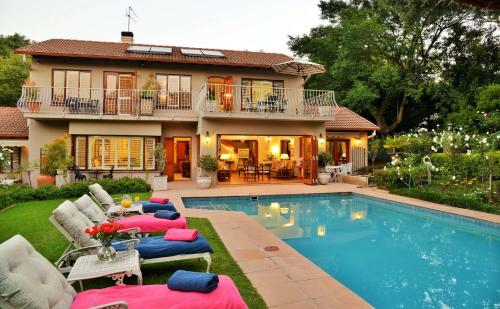 a house with a swimming pool and a house at Bellgrove Guest House Sandton in Johannesburg