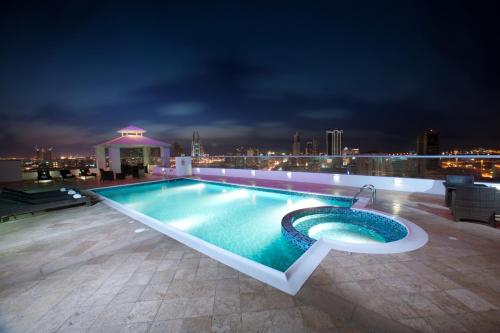 a swimming pool on the roof of a building at night at Al Olaya Suites Hotel in Manama