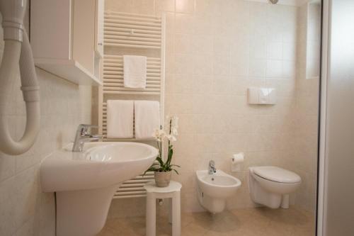 a white bathroom with a sink and a toilet at Agritur Comai in Riva del Garda