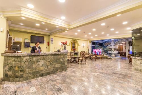 a woman standing at a bar in a lobby at Capital Plaza Hotel in Sucre
