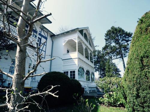 a white house with a tree in the yard at "Rheinschlosschen" Villa am Meer in Göhren