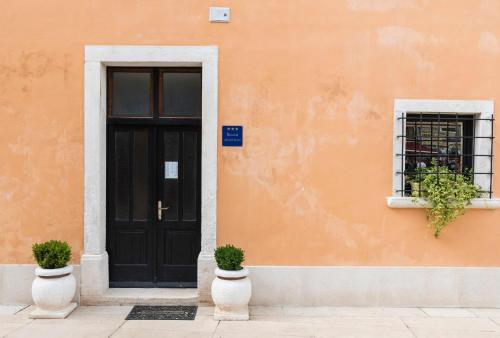 un edificio arancione con una porta nera e una finestra di App Paris 2 a Umag (Umago)