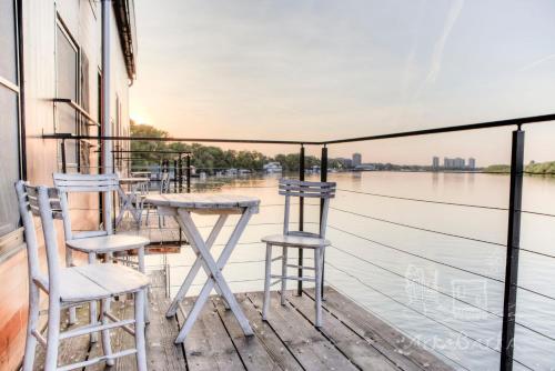 a balcony with chairs and a table and a view of the water at ArkaBarka 2- Floating Dream Rooms and Apartments in Belgrade