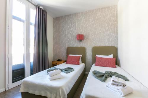 two beds in a room with a window at Guest House Porto Clerigus in Porto