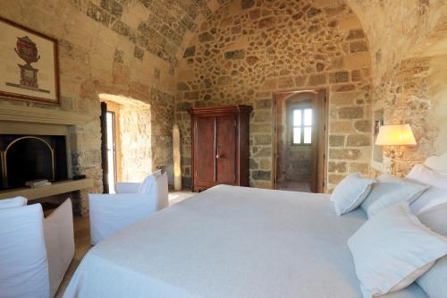 a bedroom with a white bed in a stone wall at Masseria Fano Relais & Wine in Salve