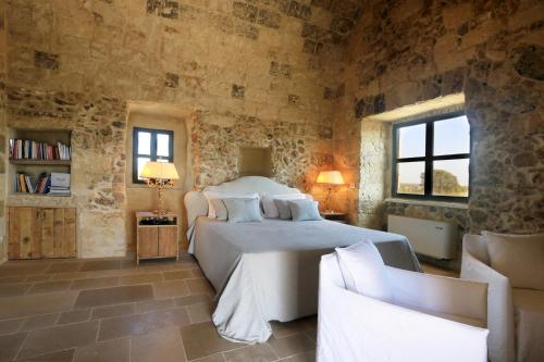 a bedroom with a bed in a stone wall at Masseria Fano Relais & Wine in Salve