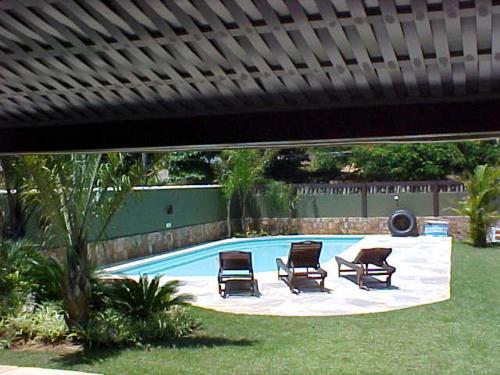 una piscina con 2 sillas en Casa em Búzios Geribá luxo 5 suites, en Búzios