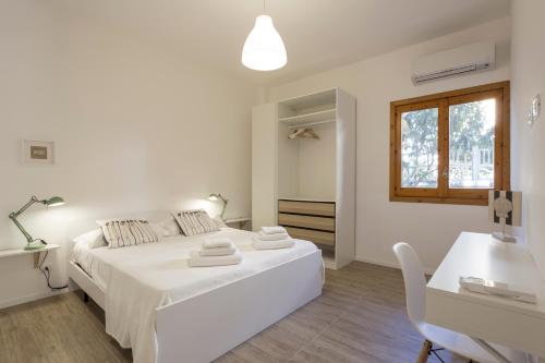 a white bedroom with a white bed and a desk at BOBO' in Marina di Ragusa
