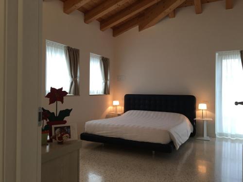 ein Schlafzimmer mit einem Bett und zwei Fenstern in der Unterkunft Quirinus Venetia Properties in Mestre