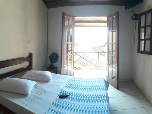 a bedroom with a bed and a large window at Jambeiro na praia in Trindade