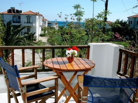 einen Holztisch mit einer Vase aus Blumen auf dem Balkon in der Unterkunft Korali in Órmos Marathokámpou