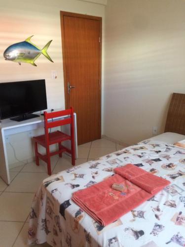 a bedroom with a bed and a desk with a fish on the wall at Casa da Jussara in Itaperuna