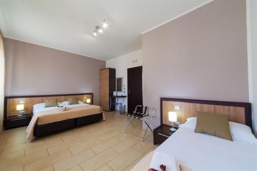 una habitación de hotel con 2 camas y una silla en Kristal, en San Vito lo Capo
