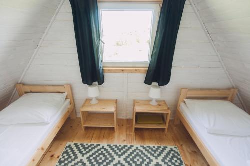 ウストカにあるDomki Letniskowe Skandynawiaのベッド2台と窓が備わる小さな客室です。