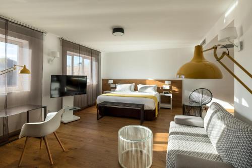 a bedroom with a bed and a couch and a tv at Rafaelhoteles Atocha in Madrid