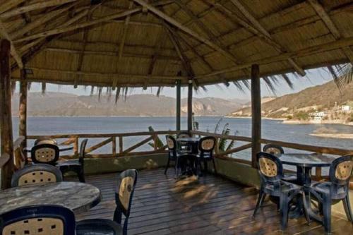 a porch with tables and chairs and a view of the water at Hotel Del Dique in Coronel Moldes