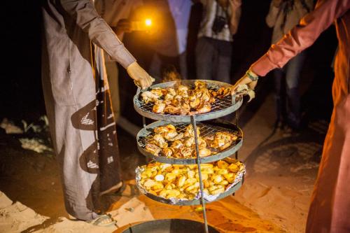 a person holding three plates of food on a stand at Arabian Nights in Wadi Rum